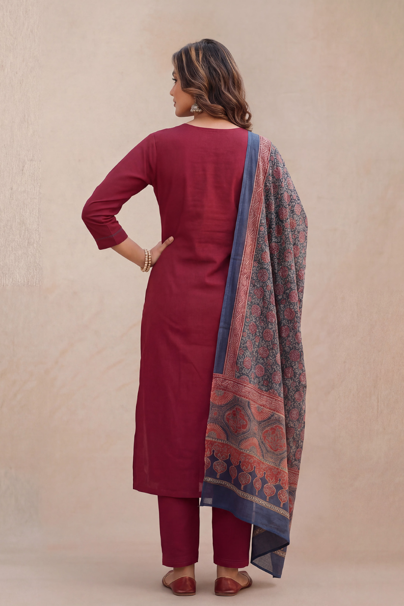 Woman wearing a maroon kurta with a patterned dupatta on a beige background