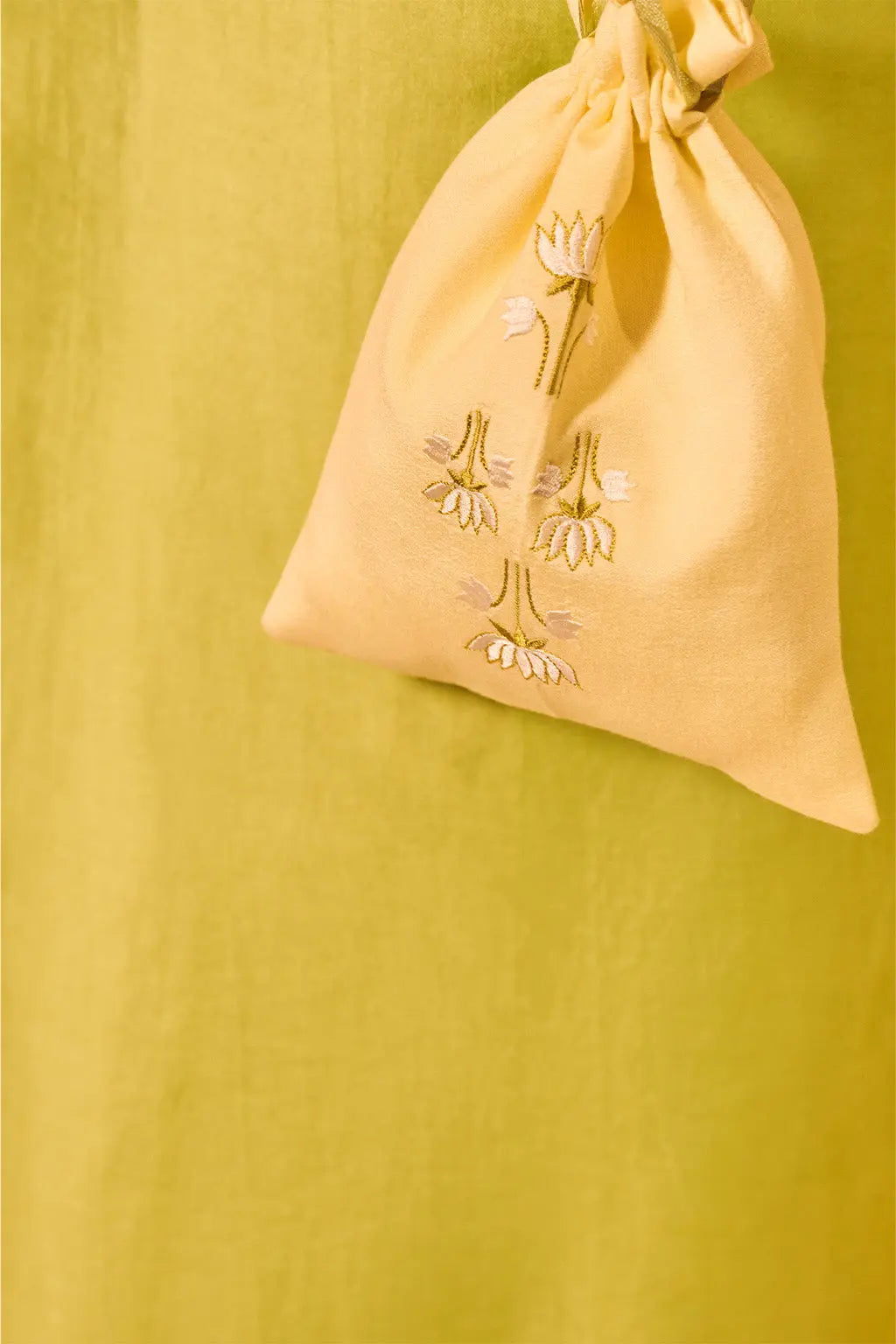 Close-up of embroidered potli bag paired with lime green sleeveless ethnic co-ord set for women