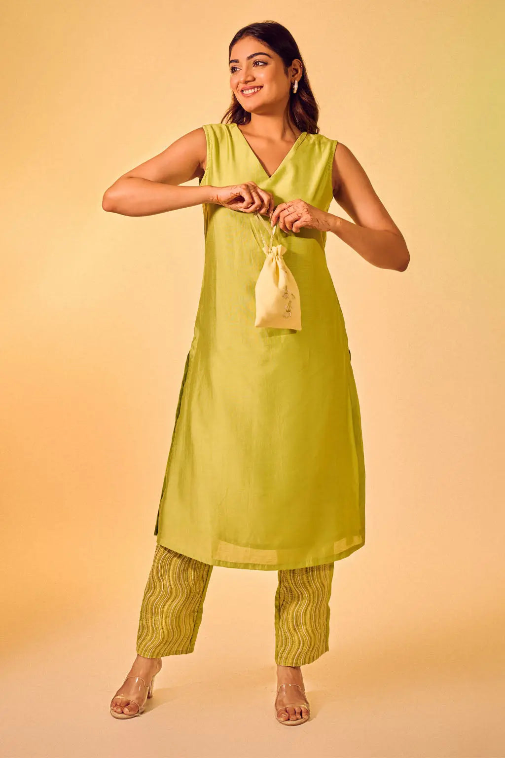 Woman wearing lime green sleeveless kurta pant set with V-neck design and printed pants