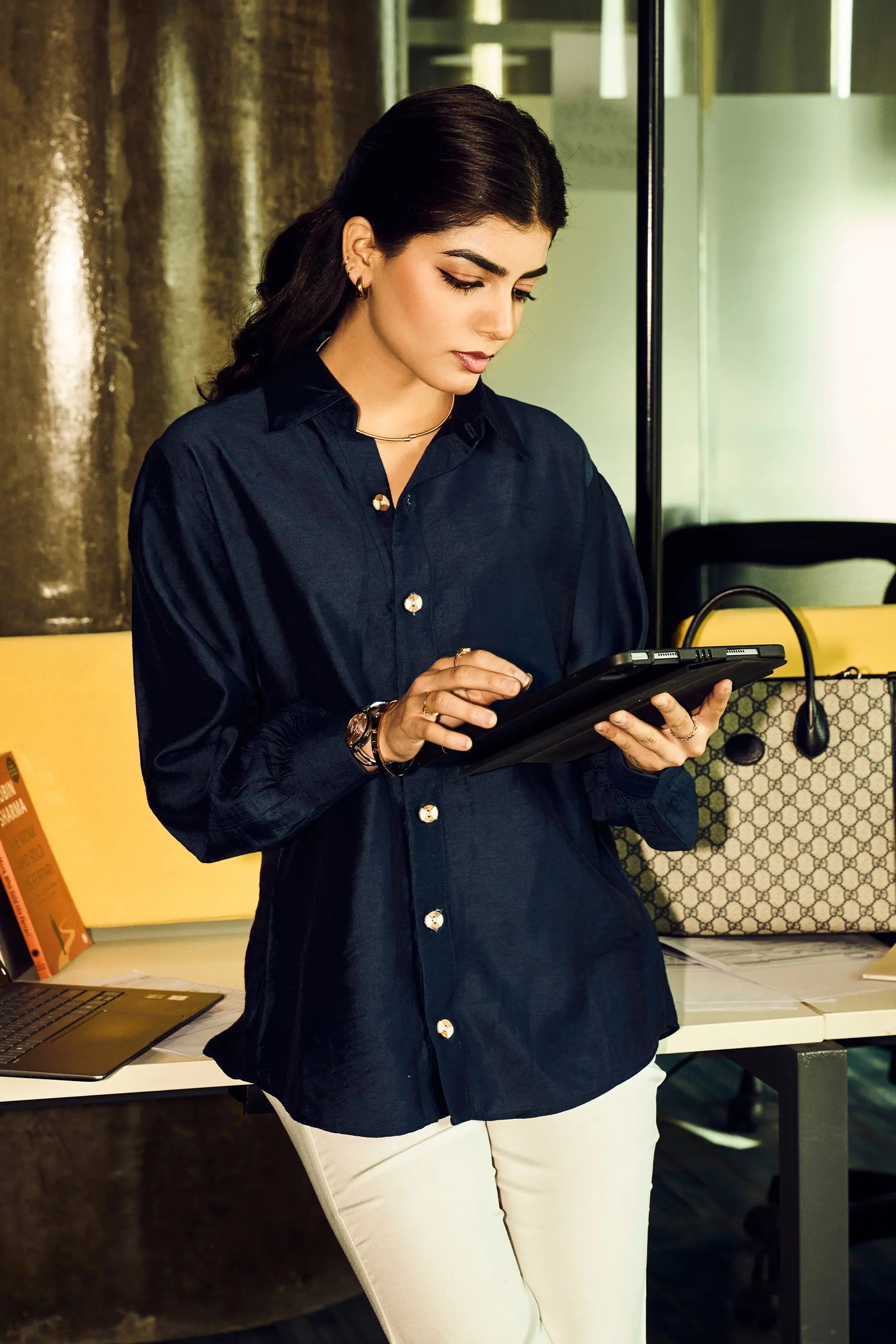 Woman wearing a navy blue Chanderi regular fit shirt styled with white pants for office wear