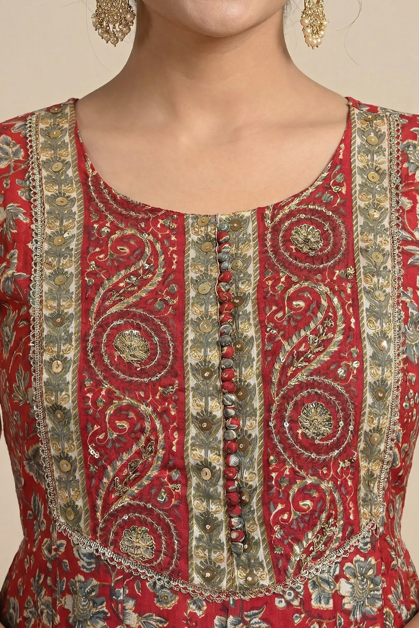 Woman wearing red printed Anarkali kurta set with matching dupatta and pants for festive wedding ethnic wear featuring traditional floral prints and embroidered detailing