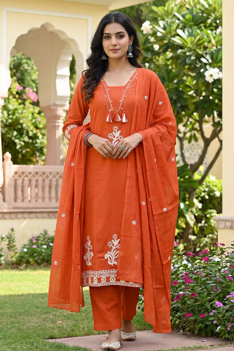 Women wearing rust orange embroidered kurta set with matching dupatta and straight pants in garden setting