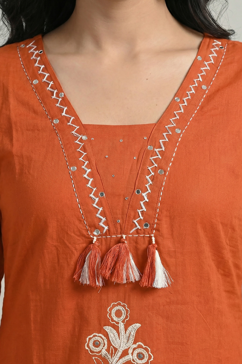 Women wearing rust orange embroidered kurta set with matching dupatta and straight pants in garden setting
