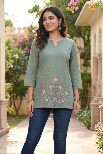 Woman wearing sage green cotton short kurti with floral print and jeans in outdoor garden setting for casual wear